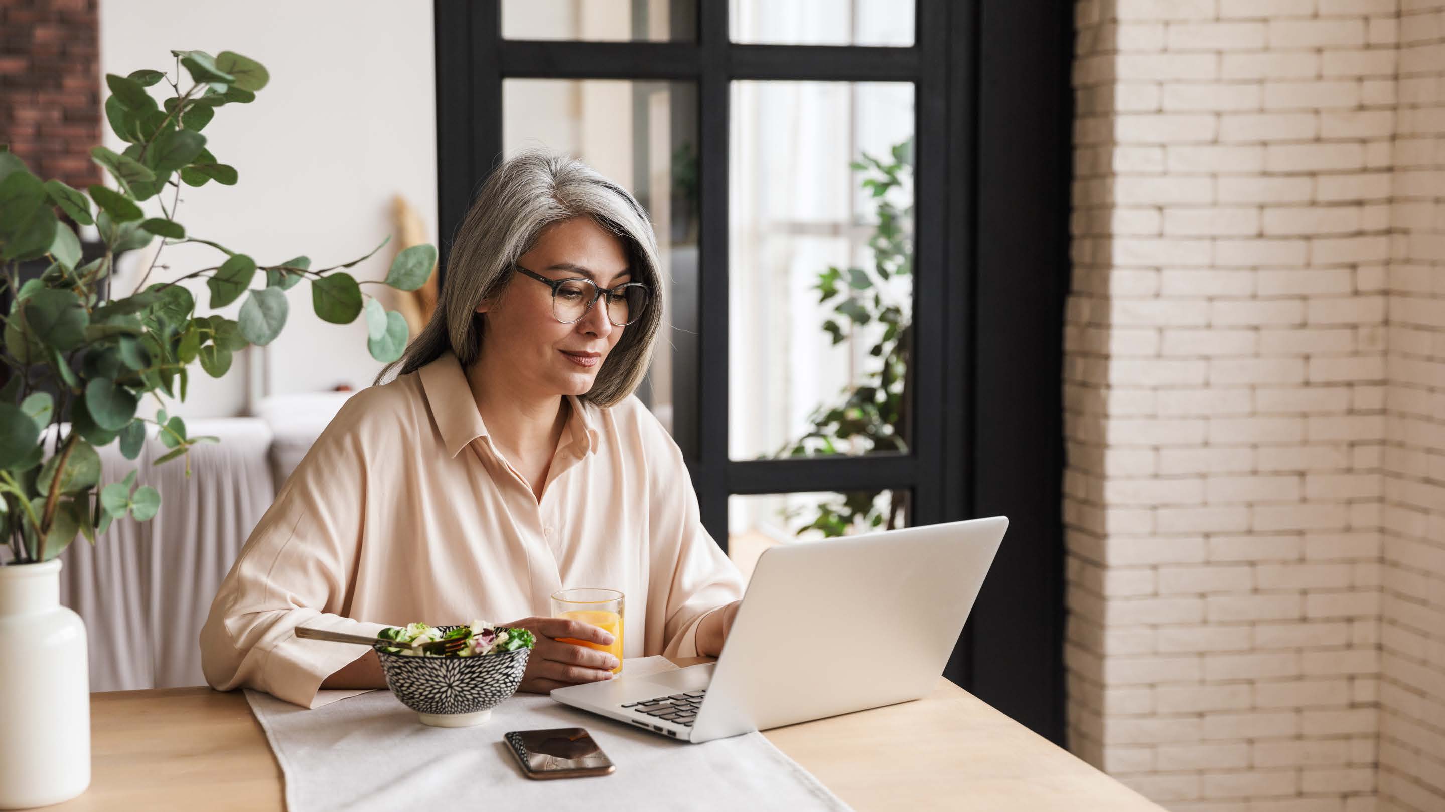 Woman Using Laptop On Dining Table